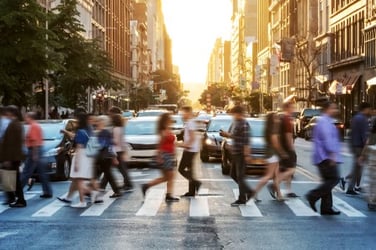 People walking across a busy street in a city in a cross-walk.