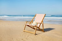 An empty chair on the beach, symbolizing relaxation and financial security through retirement plans for small businesses. Keywords: Retirement plan, SECURE 2.0 Act, employee benefits.