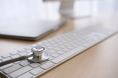 This image shows a stethoscope resting on a computer keyboard