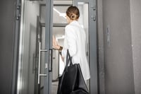 Young business woman in white suit entering to the hall of the modern residential building.