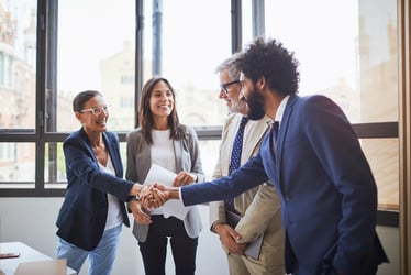 A group of people in an office shaking hands 