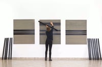 person hanging art in a gallery