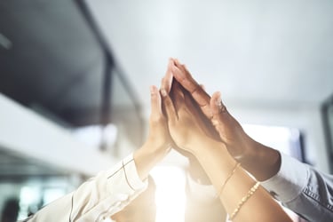   This photo represents people joining hands in support of DE&I and Pride Month, highlighting the importance of LGBTQ+ inclusion and legal considerations.