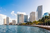 Urban Skyline Reflecting in Water: Commercial Property Insurance Insights - Tall buildings stand tall behind a body of water, symbolizing the challenges and considerations in insuring commercial properties. 