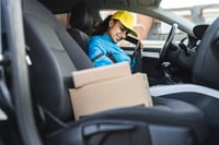 A women buckling her seatbelt with packages on the passengers seat