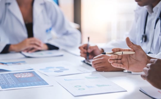 Team_ medical analysts and doctors consulting with paperwork of graphs_ data and charts in hospital conference room. Closeup of healthcare staff discussing statistics_ results and innovation strat
