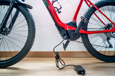 A red electric bicycle plugged into a charger. The e-bike is leaning against a white wall, with its kickstand down. The charger is plugged into a power outlet on the wall, and it has a red light on, which likely means that the bike is charging. a red electric bicycle plugged into a charger. The bike is leaning against a white wall, with its kickstand down. The charger is plugged into a power outlet on the wall, and it has a red light on, which likely means that the bike is charging. E-bike and e-scooter fires on the rise — posing risk to homes.